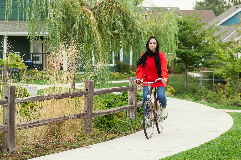 Woman riding bicycle alongside greenery