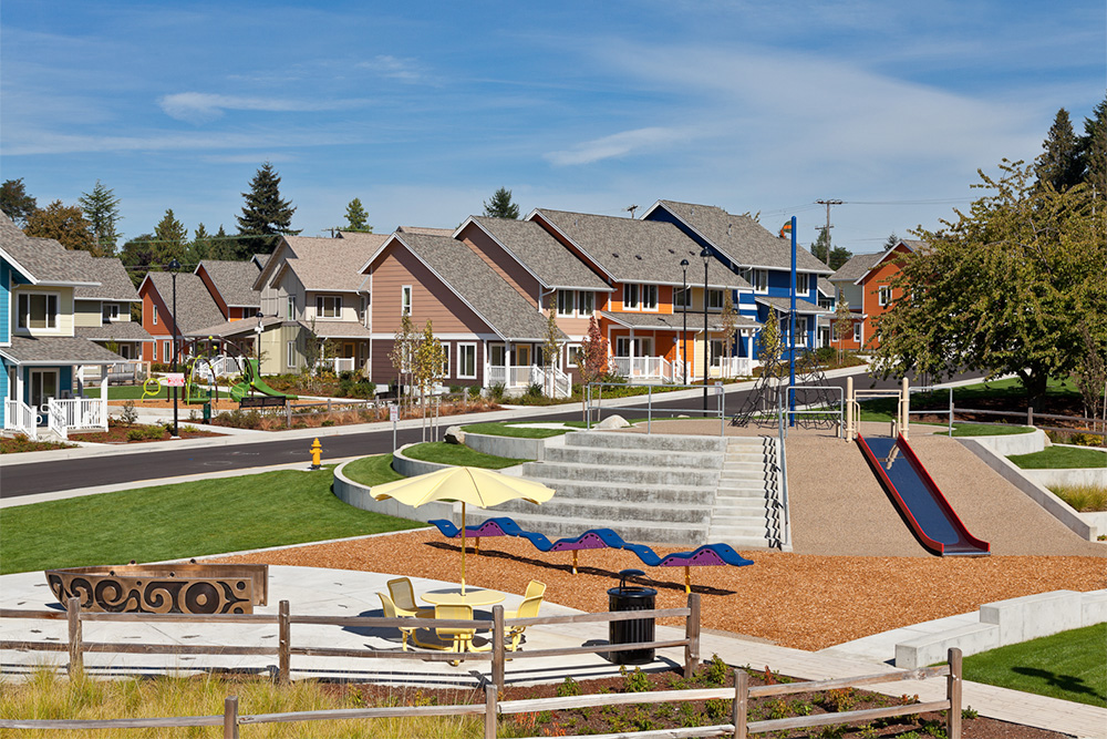 Park with play structures; a group of homes sit behind it