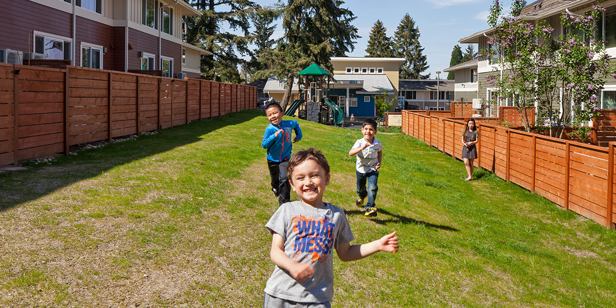 Children playing in grass near apartment buildings