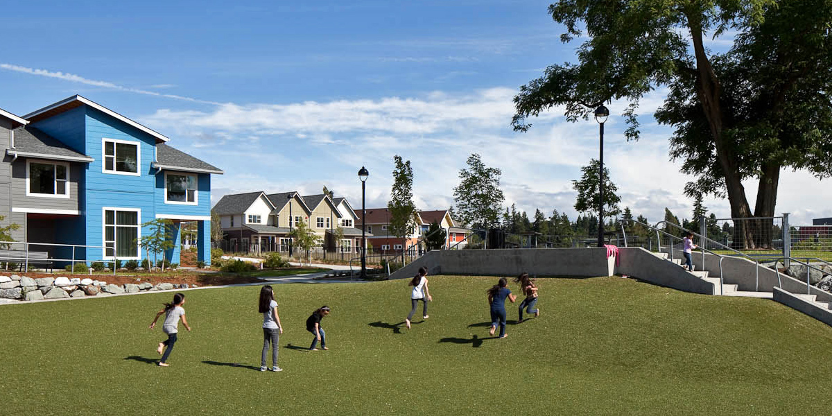 Children playing on the grass in front of rental housing at Greenbridge